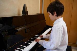 elementar Alter Junge Musiker Pianist genießt das Rhythmus von klassisch Musik- während Theaterstücke Klavier. Hobbys und Freizeit foto
