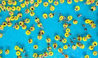 oben Aussicht von Menschen entspannend im das Schwimmbad auf Gelb aufblasbar Kreise foto