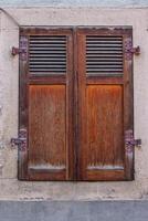 Land Stil Fenster mit geschlossen uralt retro hölzern Fensterläden. Antiquität Deutsche historisch Haus im Bayern. schäbig geknackt texturiert Mauer. historisch und atmosphärisch Architekt Element. Vorderseite Aussicht foto