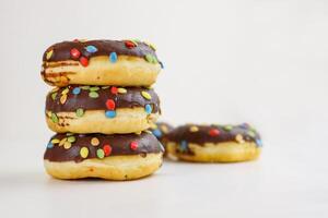 ein Stapel von Donuts glasiert mit Schokolade und bunt Smarties. Stapel von 5 Donuts isoliert auf ein Weiß Hintergrund. Seite Sicht. Kopieren Raum foto