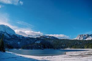 schneebedeckt Ufer von das schwarz See beim das Fuß von das Berge. Durmitor National Park, Montenegro foto