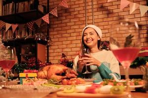 Junge kaukasische Frau lächelt in einem Diner mit besonderen Speisen wie gebratenem Truthahn und Wein in der Weihnachtsfeier im Speisesaal, der für ein fröhliches Festival und ein frohes neues Jahr dekoriert ist. foto