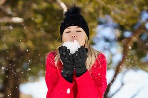 blonde frau, die im winter einen schneeball bläst, in sierra nevada, granada, spanien. foto