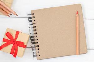 Notizbuch mit Rotstift und Geschenkbox auf weißem Holz foto