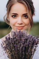 Mädchen in einem weißen Sommerkleid und ein Typ in einem weißen Hemd auf einem Spaziergang bei Sonnenuntergang mit einem Blumenstrauß foto