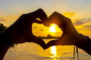 Herz gemacht von Hände mit Türkis Wasser und Sonnenuntergang Malediven. foto