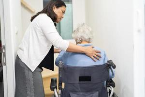 Pflegekraft hilft asiatischen oder älteren alten Frauen, die im Rollstuhl sitzen, die Treppe im Haus hinauf zu stützen. foto