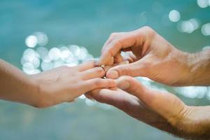 Die Hand eines Mannes legt einen Ehering auf die eines Mädchens foto
