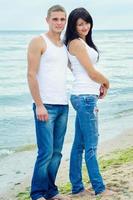 Typ und ein Mädchen in Jeans und weißen T-Shirts am Strand foto