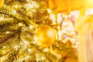 ein Weihnachten Baum mit Gold Ornamente und Beleuchtung. das Baum ist dekoriert mit Gold Bälle und ist zündete oben mit Beleuchtung. das Baum ist platziert im ein Zimmer mit ein Fenster foto