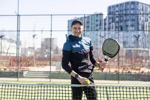 Mann spielen Padel im ein Grün Gras Padel Gericht Innen- hinter das Netz foto