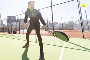 Mann spielen Padel im ein Grün Gras Padel Gericht Innen- hinter das Netz foto