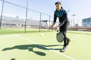 Mann spielen Padel im ein Grün Gras Padel Gericht Innen- hinter das Netz foto