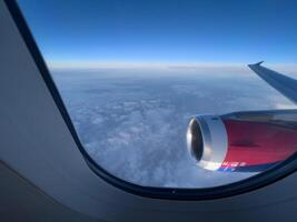 Aussicht von das Fenster auf das Turbine und das Flügel von ein Flugzeug fliegend über das Wolken foto