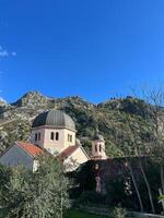 Kuppeln von das Kirche von st. Nikolaus gegen das Hintergrund von Grün Berge. Kotor, Montenegro foto