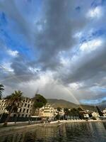 Regenbogen Über das Meer Küste von ein Resort Stadt, Dorf in der Nähe von das Berge foto