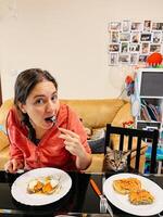 jung Frau Essen Toast mit Lachs, Avocado, pochiert Ei und Käse während Sitzung beim das Tabelle beim Zuhause foto