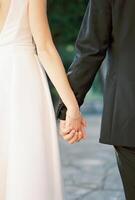 Braut und Bräutigam sind Stehen halten Hände. zurück Sicht. abgeschnitten foto