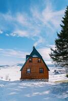 Rauch steigt an von das Kamin von ein hölzern gemütlich Haus im ein schneebedeckt Dorf foto