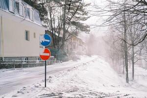 halt und Umleitung Straße Zeichen Stand auf ein schneebedeckt Straße in der Nähe von ein Gebäude foto