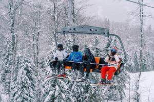 Skifahrer im Ski Anzüge und Helme Reiten oben ein schneebedeckt Steigung auf ein Ski Aufzug foto