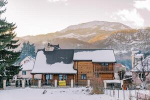 zwei Geschichte hölzern Hütte im ein schneebedeckt Dorf beim das Fuß von das Berge foto