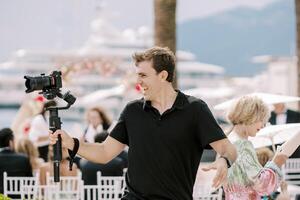 lächelnd Fotograf nehmen Bilder von ein Hochzeit Zeremonie während halten ein Digital Kamera im seine Hand auf ein Stand foto