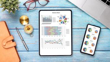 ein Tablette und ein Telefon sind auf ein Tabelle mit ein Notizbuch und ein Stift. das Tablette hat ein Graph auf Es, und das Telefon hat ein Kuchen Diagramm. das Szene schlägt vor Das jemand ist Arbeiten auf ein Projekt oder Analysieren Daten foto