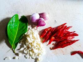 geschnitten Chilischoten, geschnitten Zwiebeln und Bucht Blätter auf ein Schneiden Tafel wie Kochen Gewürze zum traditionell indonesisch Essen foto
