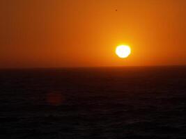 dunkel Sonnenuntergang Über das Ozean Orange und schwarz foto