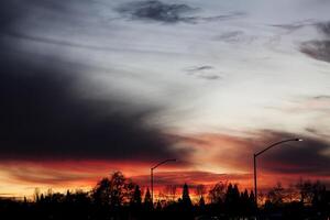 wolkig Himmel Sonnenuntergang mit Straße Lampen und Bäume foto