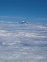 schneebedeckt Berg Gipfel stupsen Über Wolke Schicht von Flugzeug foto