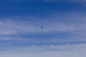 entfernt Schuss von kommerziell Verkehrsflugzeug im wolkig Blau Himmel foto