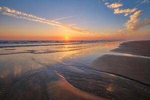 atlantisch Ozean Sonnenuntergang mit wogend Wellen beim fonte da telha Strand, Portugal foto