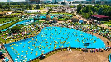 oben Aussicht von Menschen entspannend im das Schwimmbad auf Gelb aufblasbar Kreise und Sonne Betten auf das Strand foto