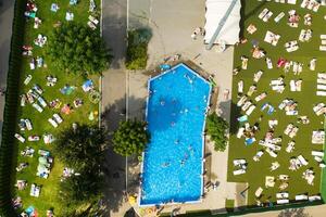 oben Aussicht von ein draussen Platz zum Menschen zu entspannen wo Dort ist ein Schwimmen Schwimmbad und ein Menge von Sonne Betten foto