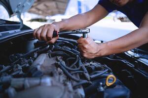 Nahansicht von ein Auto Mechaniker reparieren ein Auto im ein Garage, Auto Sicherheit prüfen das Motor im das Garage, Reparatur Bedienung Konzept. foto