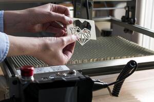 Laser- Gravur und Schneiden, Frau halten ein Beispiel von ein Schnitt aus hölzern Herz foto