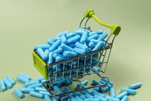 Blau Medizin Kapsel im Miniatur Einkaufen Wagen foto