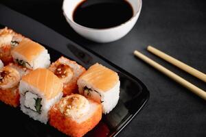 Satz Sushi-Rolle auf schwarzem Teller. Servieren von japanischem Essen im Restaurant. foto