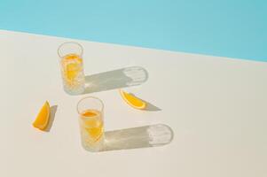 Sommer- Szene gemacht mit zwei Brille von erfrischend trinken mit Scheiben von frisch Orange auf hell Beige und Pastell- Blau Hintergrund. minimal Konzept. modisch Sommer Party Idee. Sommer- ästhetisch. foto