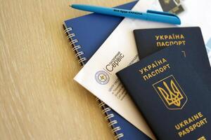 Kiew, Ukraine - - November 27, 2023 Reisepass Bedienung Logo mit International ukrainisch Reisepass und Stift foto