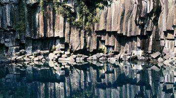 Felsen im Wasser reflektiert. erstarrte Lava in der Nähe des Wassers eines Sees auf der Insel Jeju. Südkorea foto