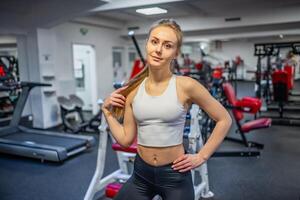 jung sportlich Frau tragen Sportbekleidung posieren Vor tun Übung mit Fitness Ausrüstung beim Fitnessstudio, sie Übung zum stark und gut foto