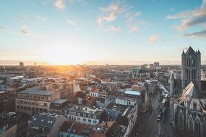 Aufpassen das Sonnenuntergang Über Gent von das historisch Turm im das Stadt Center. romantisch Farben im das Himmel. rot Licht leuchten Gent, Flandern Region, Belgien foto