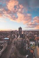 Aufpassen das Sonnenuntergang Über Gent von das historisch Turm im das Stadt Center. romantisch Farben im das Himmel. rot Licht leuchten Gent, Flandern Region, Belgien foto