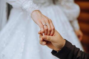 das Bräutigam Küsse das Braut Hand. Hochzeit Foto von ein Paar im Liebe. ein jung und gut aussehend Mann küssen seine Ehefrauen Hand mit ein Gold Ring, vorschlagen.