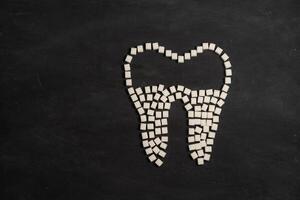 Zucker zerstören Zahn Emaille führt Zahn zerfallen Zucker Würfel bilden Zahn auf schwarz Hintergrund foto