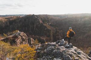 Reisender im ein Gelb Jacke Stehen auf das Kante von ein Felsen genießen ein Moment von Entspannung und ein Aussicht von das divoke sarkastisch Schlucht, Prag, Tschechisch Republik. erreichen Erfolg foto