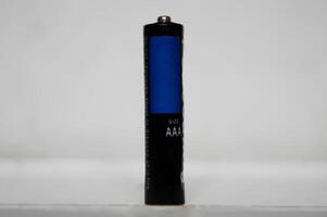 Single AAA-Größe Batterie Stehen aufrecht auf ein Weiß Oberfläche foto